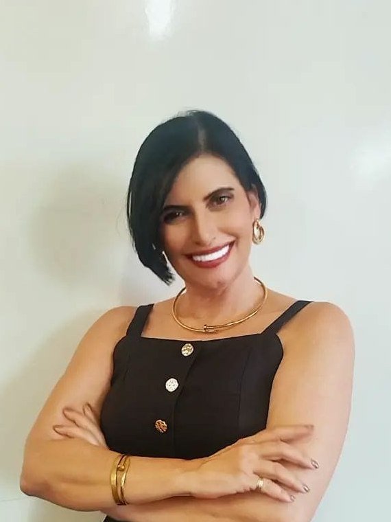 Retrato de Claudia Turatti, sorrindo, de braços cruzados