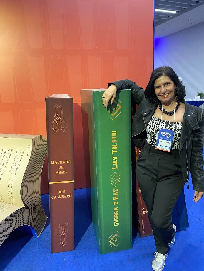 Claudia Turatti em pé entre esculturas gigantes de livros, na feira Educa