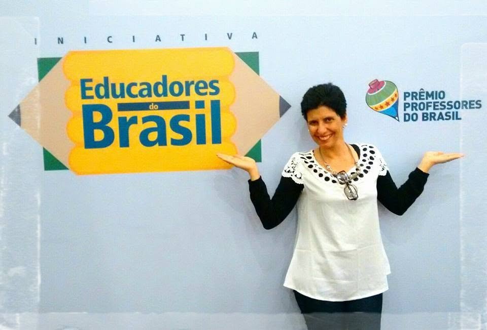Claudia Turatti ao lado do painel oficial do Prêmio Professores do Brasil