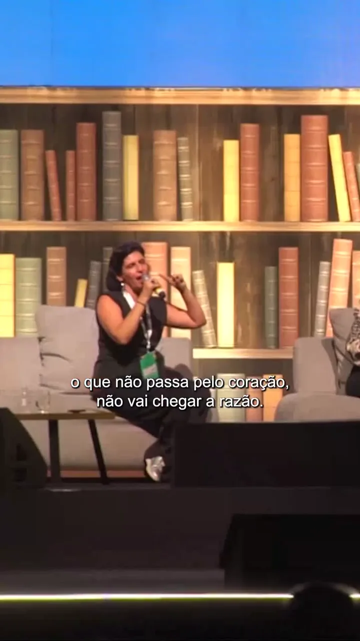 Claudia Turatti falando ao microfone no palco do Festival de Educação Liga da Gide